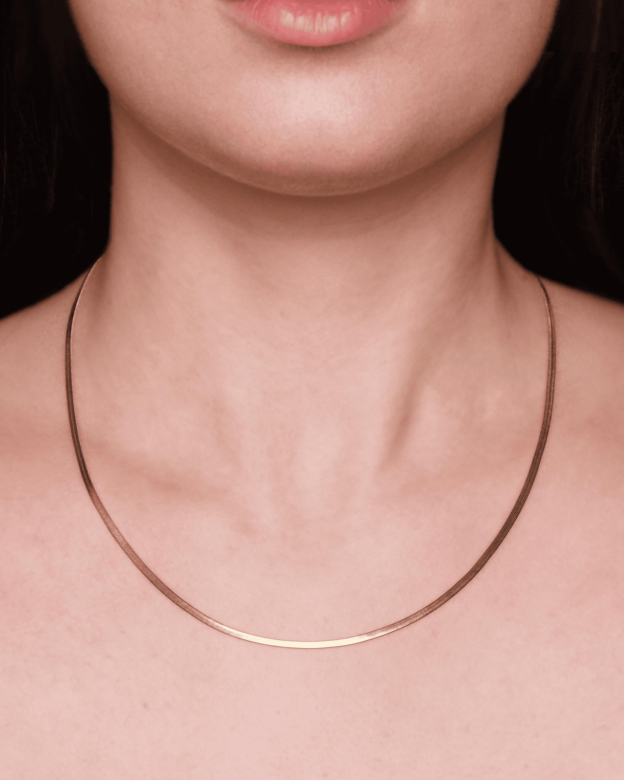 Collana sottile d'oro indossata da una persona.