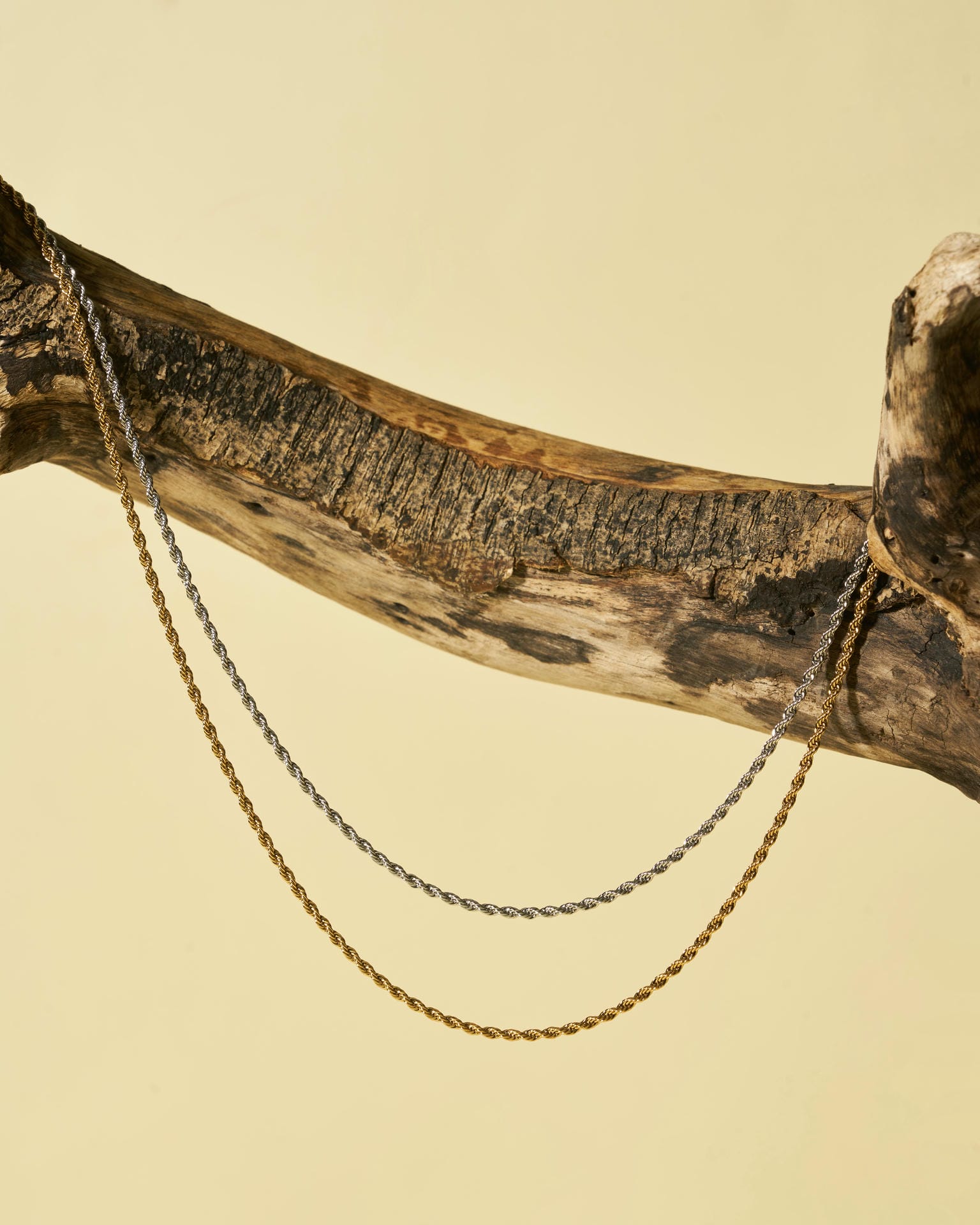 Collane d'argento e oro su ramo di legno