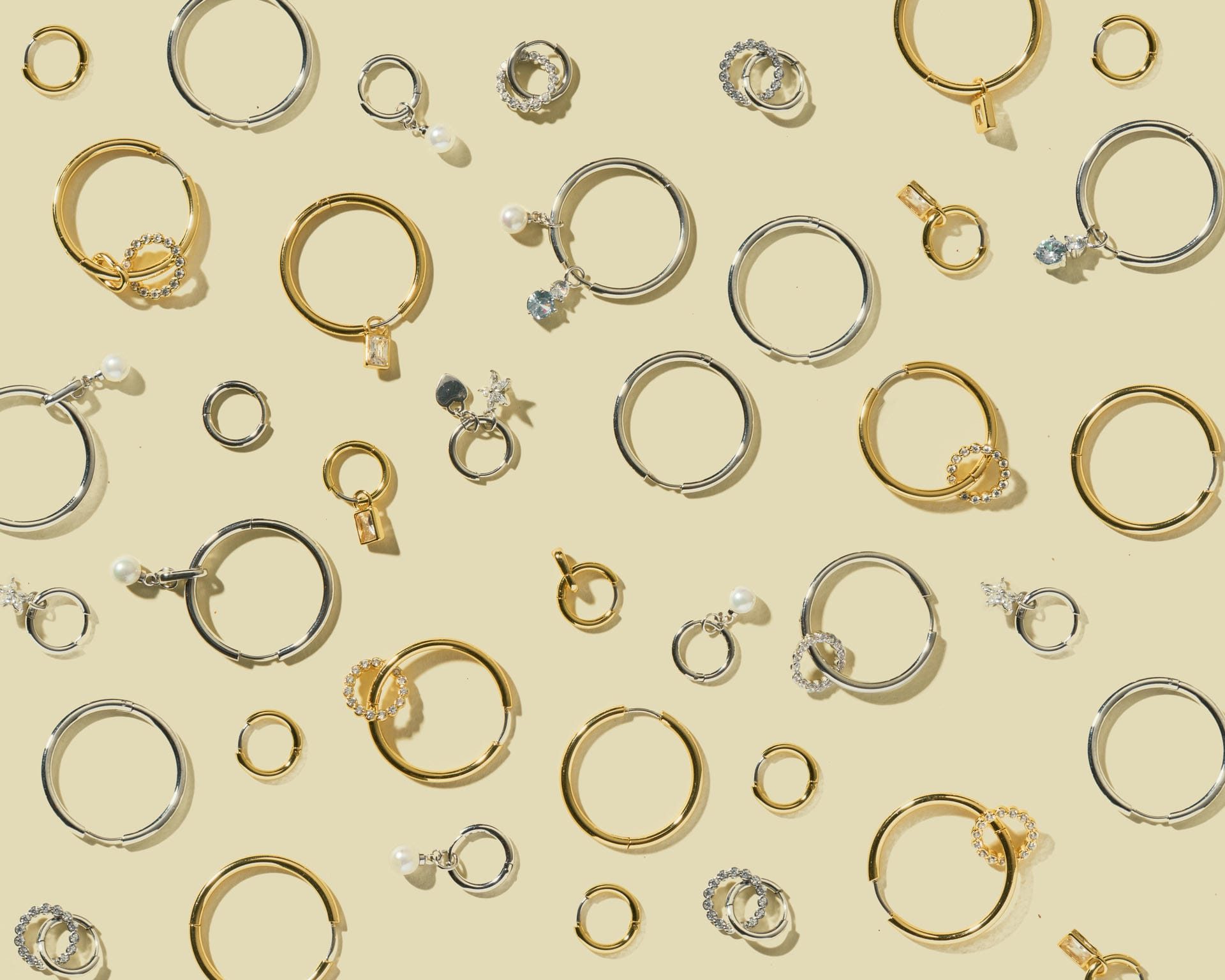 Orecchini vari in oro e argento su sfondo chiaro.